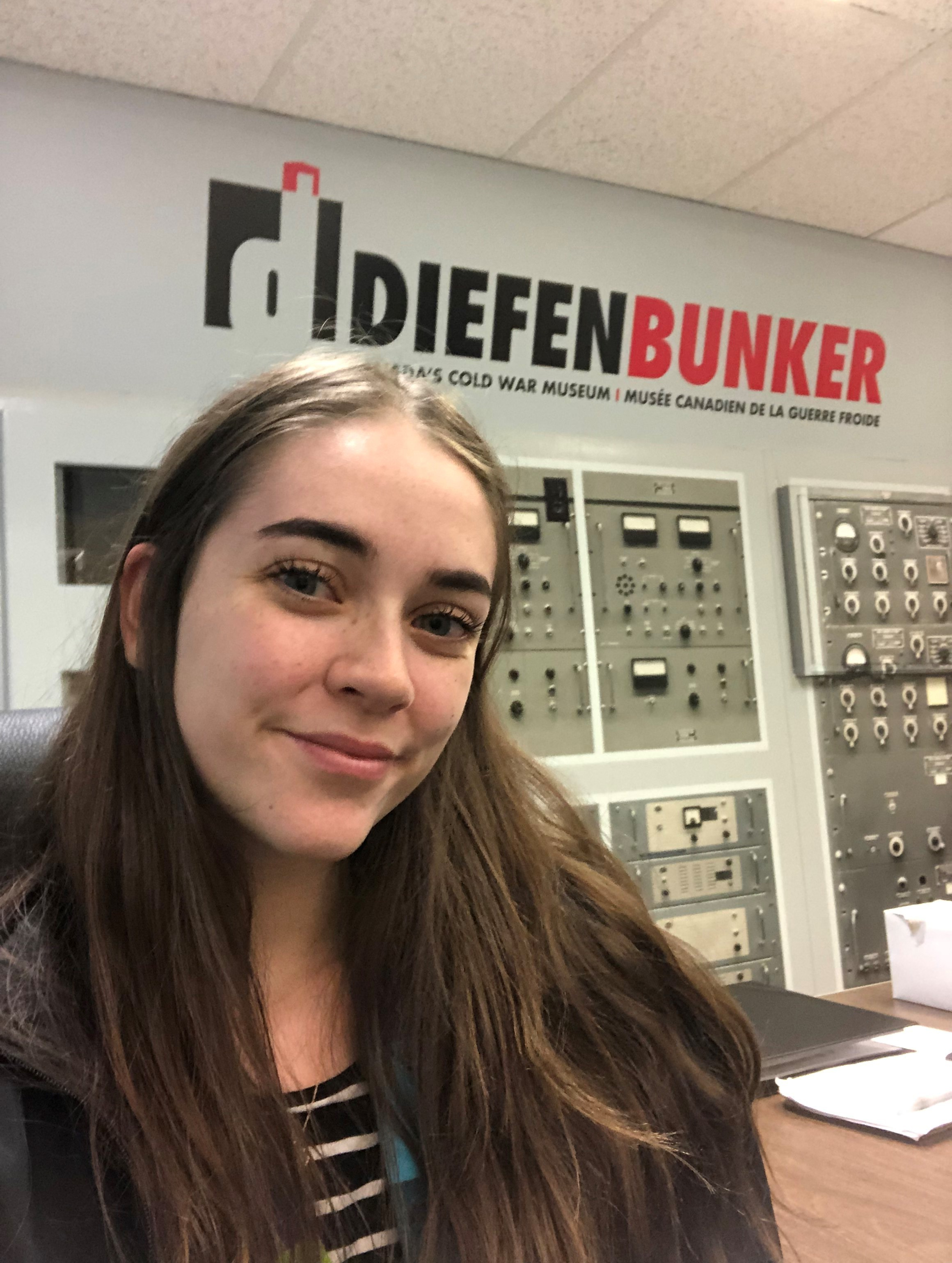 Skylar poses in front of the Diefenbunker sign located at the Welcome Desk.