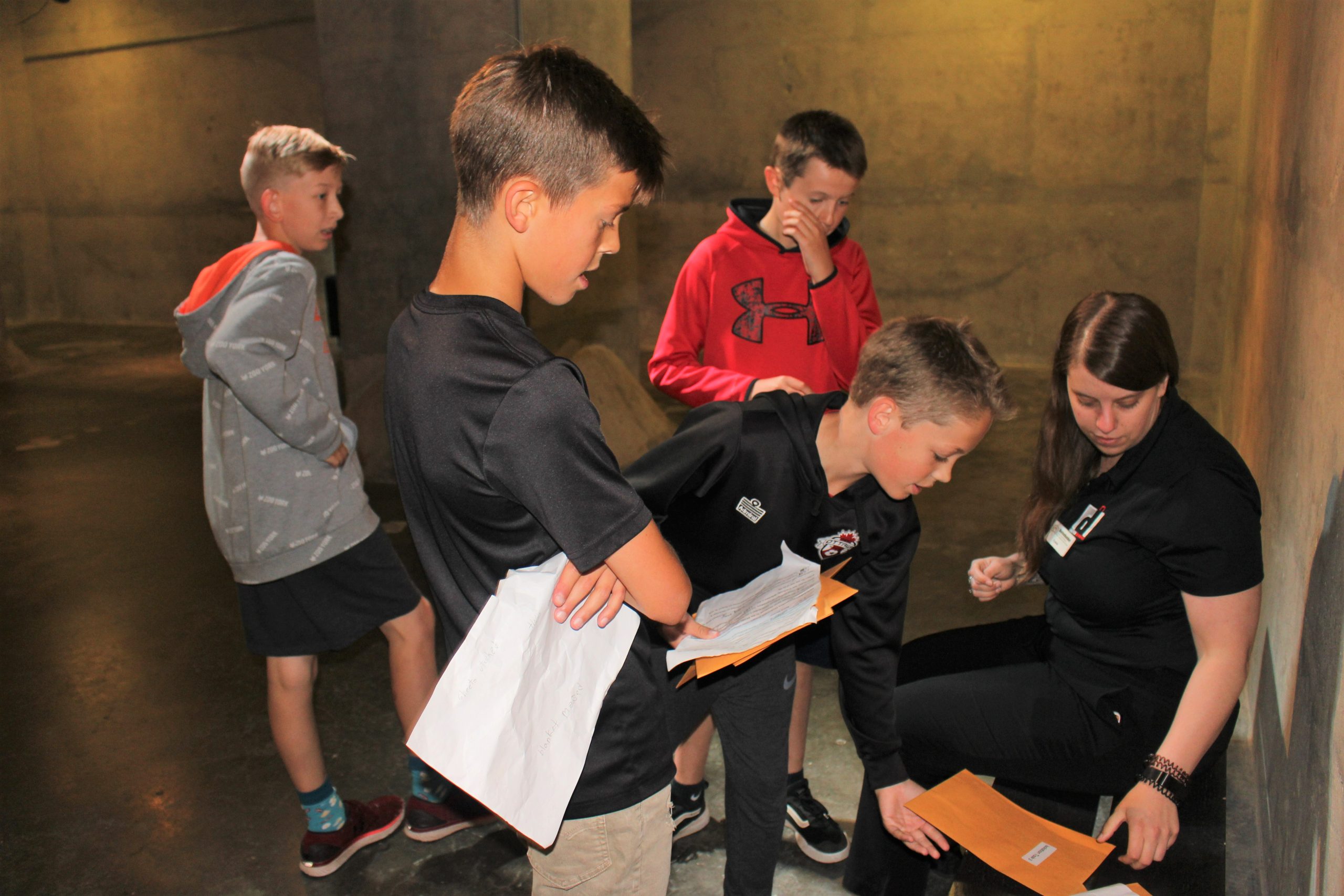 Four students huddle around a facilitator with clues outside the Bank of Canada Vault.