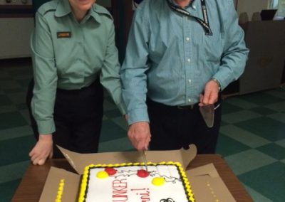 Brenda and Mike, Diefenbunker Alumni, smile while standing next to a cake.