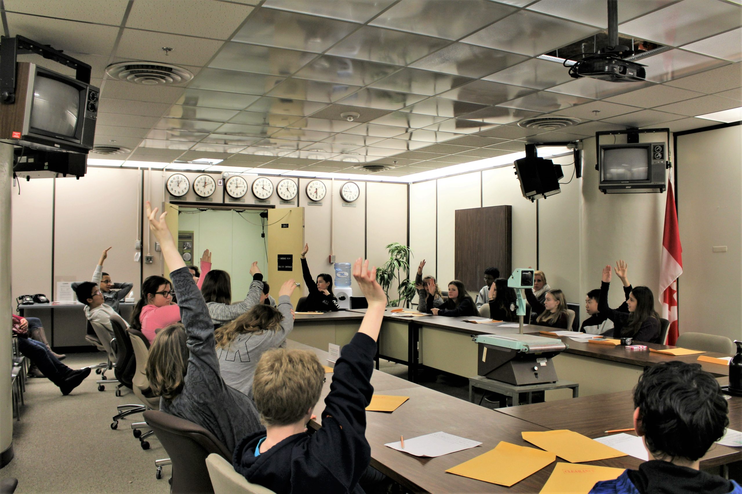 Students sit around the table in the War Cabinet Room, some of them raising their hands.