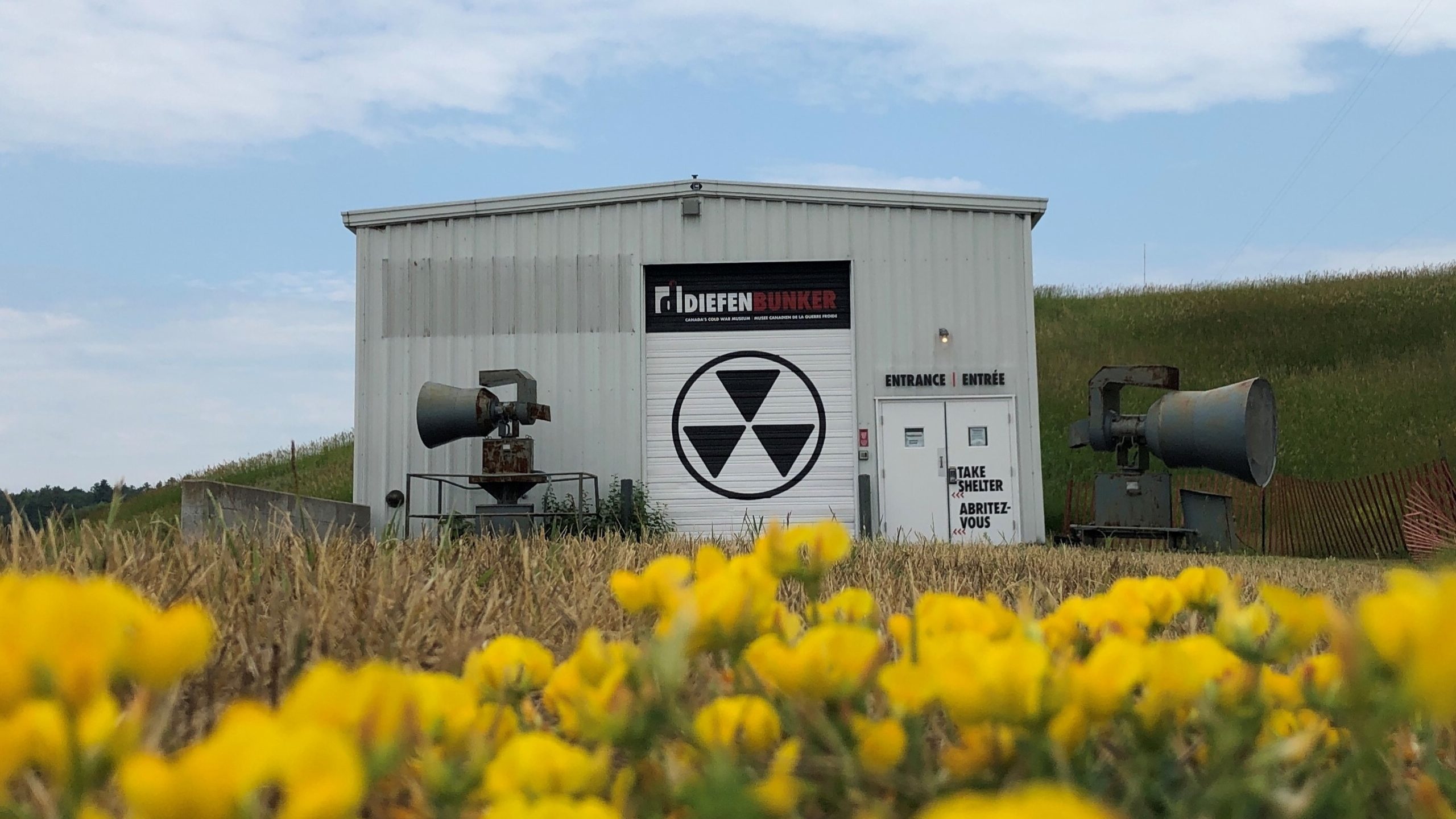 Exterior of the Diefenbunker with yellow flowers in the foreground
