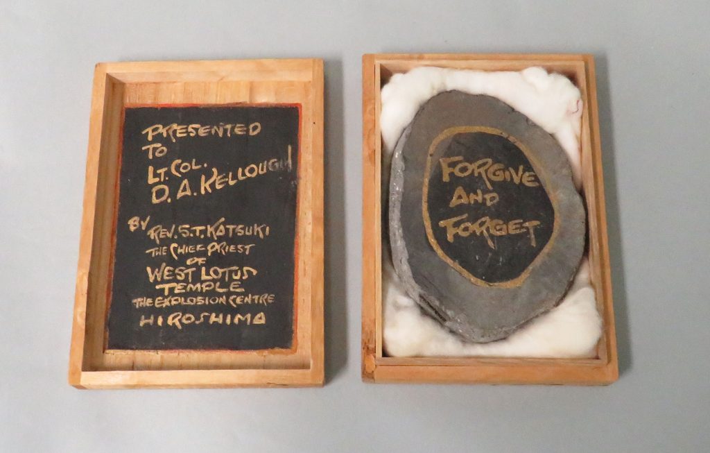 Atom Struck Tile pictured in open box. The Tile is inscribed and reads "Forgive and Forget."