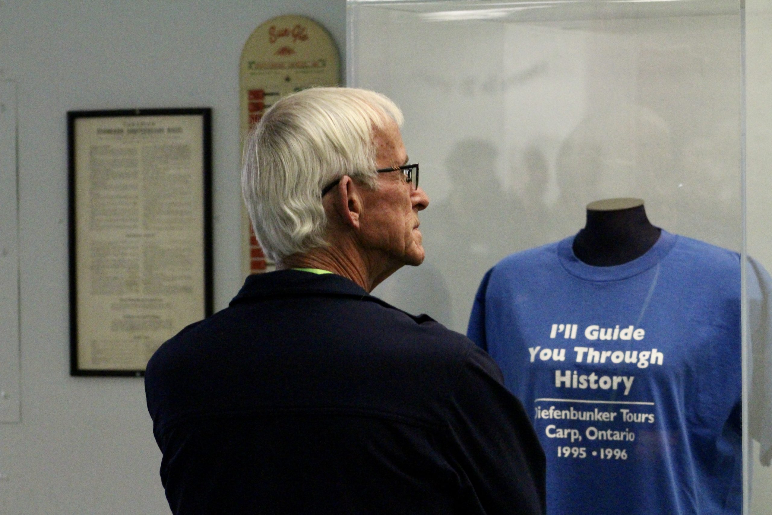 Diefenbunker supporter examines a case that displays an original Diefenbunker guide t-shirt.