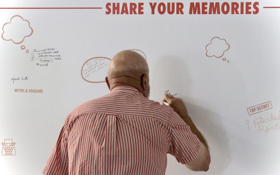 Guest writes on a board that says "Share Your Memories."