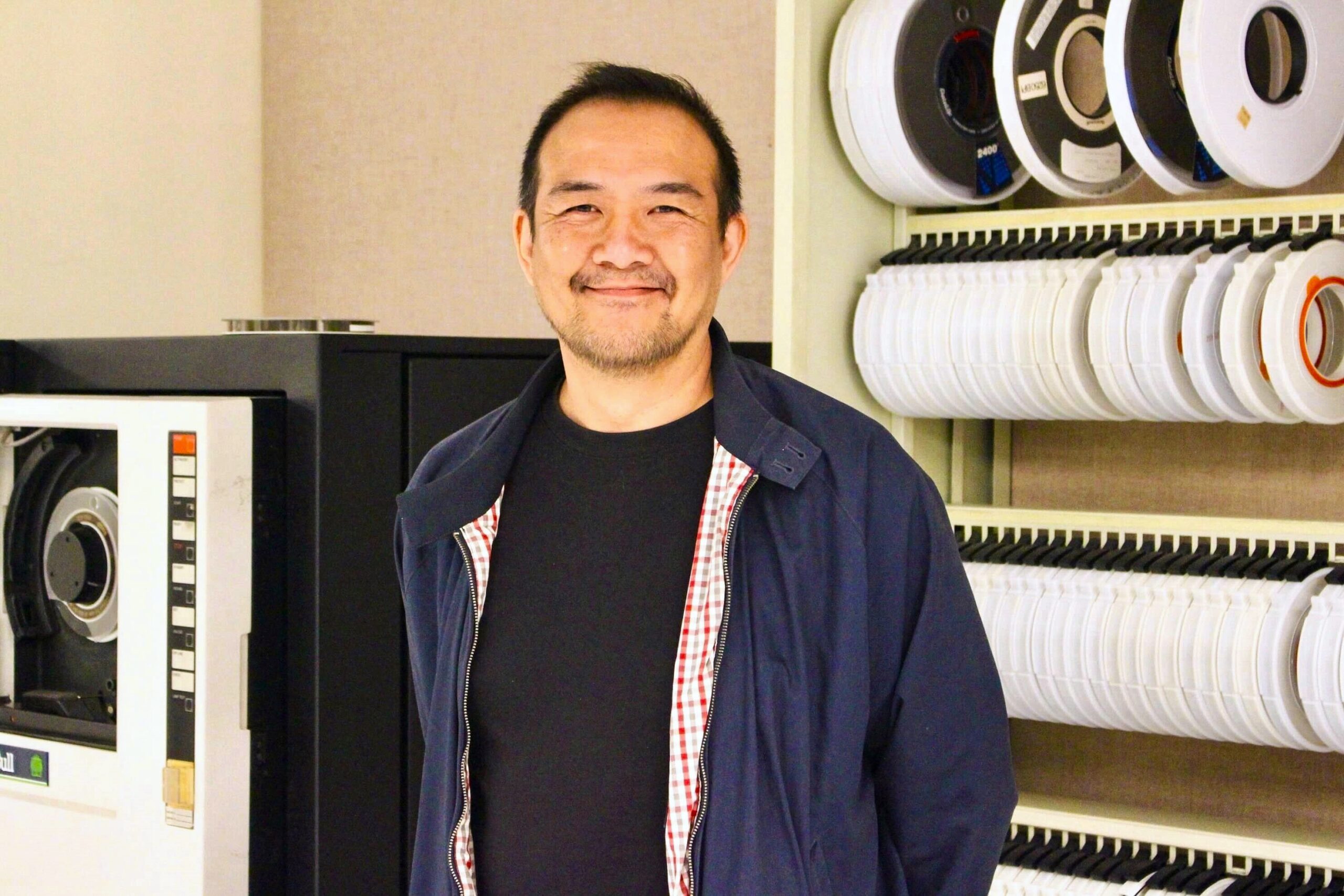 Diefenbunker 2024 Artist-in-Residence Don Kwan stands in front of historic computer equipment in the Diefenbunker.