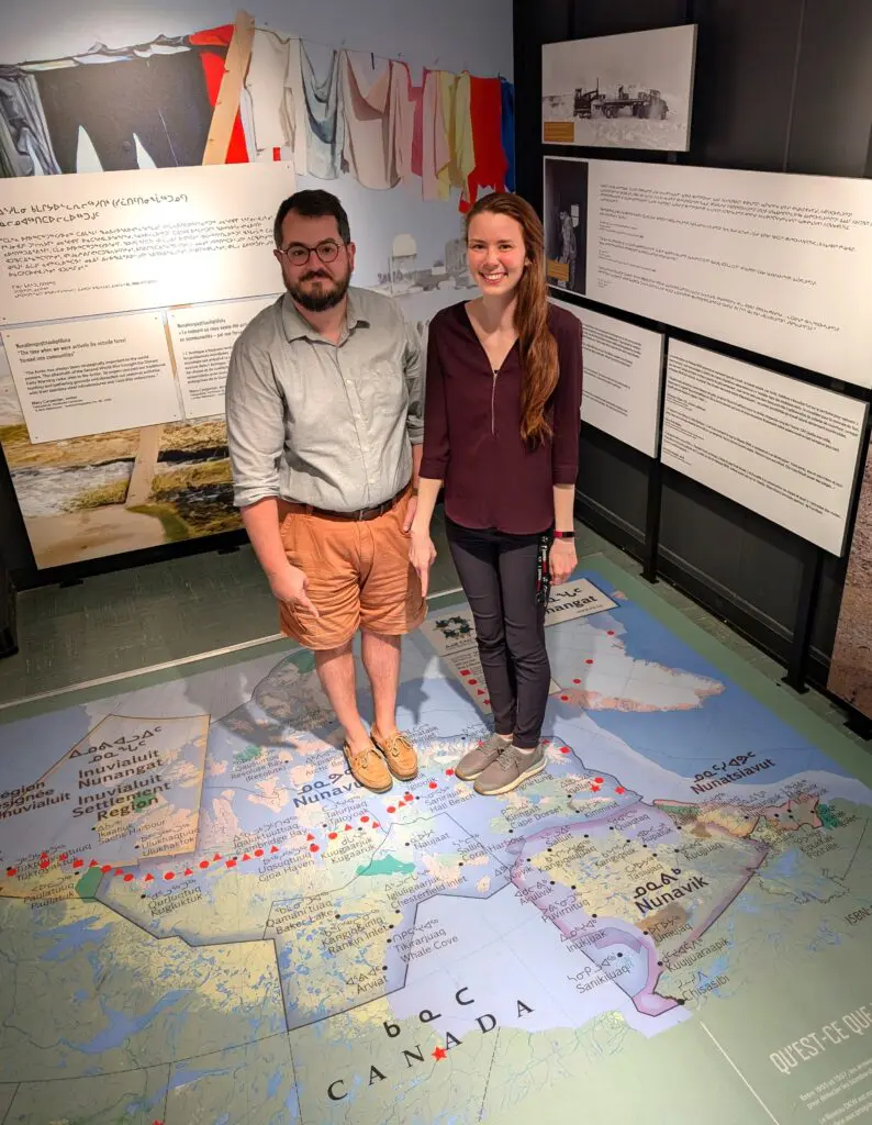 Diefenbunker staff stand on a large-scale floor map of Canada in the location of the FOX-Main DEW Line site in Sanirajak, Nunavut.