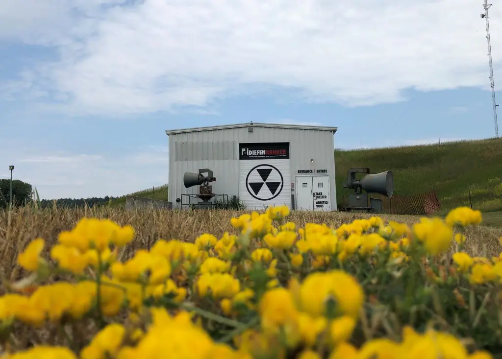 Diefenbunker exterior with yellow flowers on the hillside in front of it.