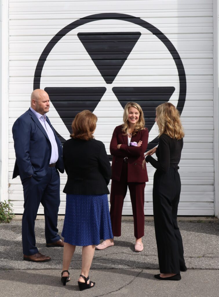 Ottawa Tourism President & CEO Michael Crockatt, Diefenbunker Board Vice President Joanne Charette, MP for Kanata-Carleton Jenna Sudds, and Diefenbunker Executive Director Christine McGuire chat with one another outside in front of the Diefenbunker.