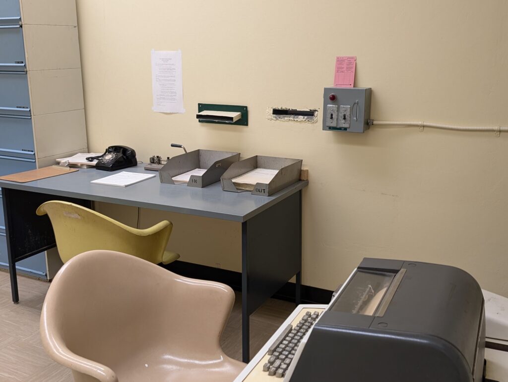 Reception desk at the Message Control Centre inside the Diefenbunker, with slots in the wall to pass encrypted messages to the next room.