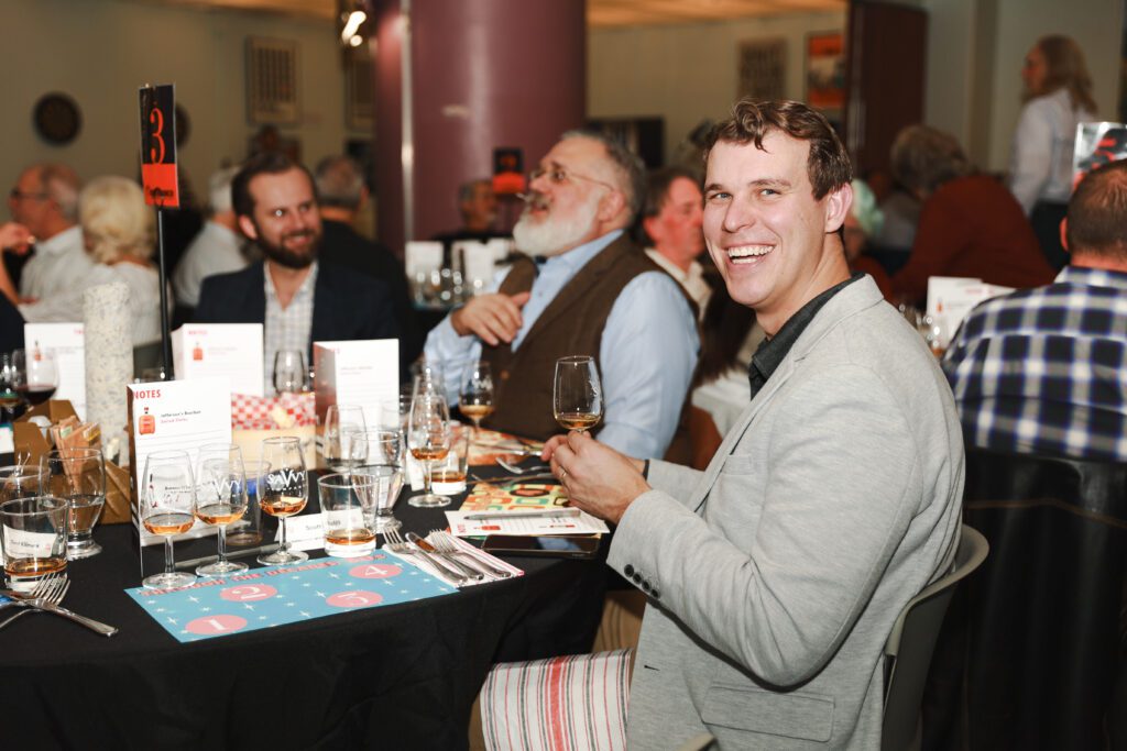 Guest smiles holding a whisky glass at the Diefenbunker's Whisky Tasting Fundraiser.