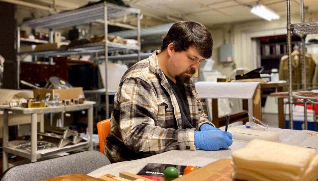 Person wearing gloves examines an artifact.