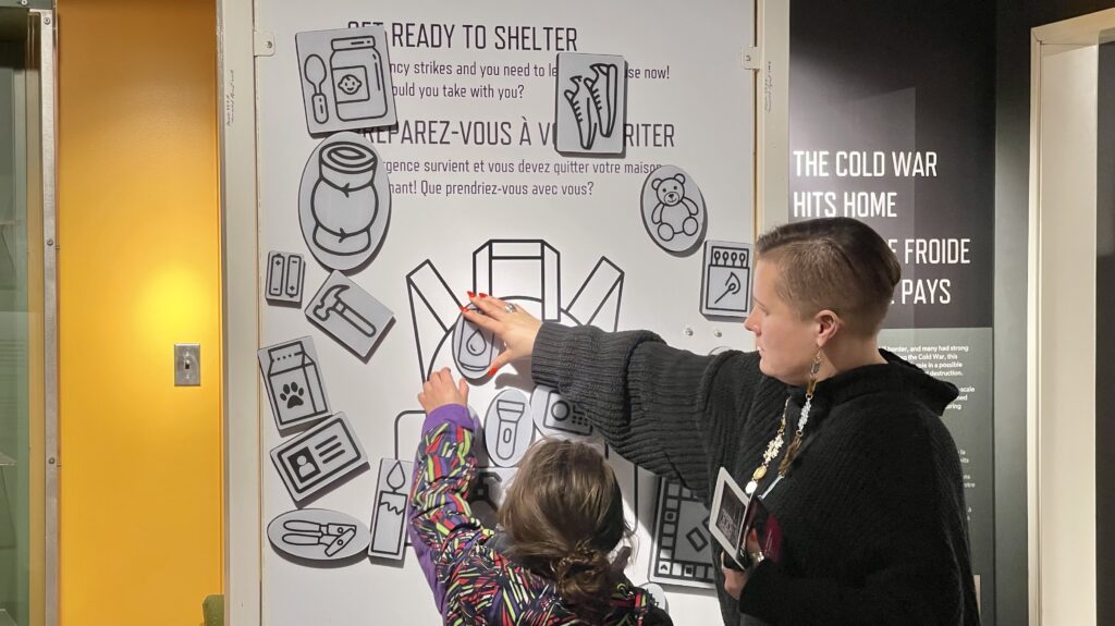 A child and parent move magnetic objects on a board to complete an emergency preparedness activity.