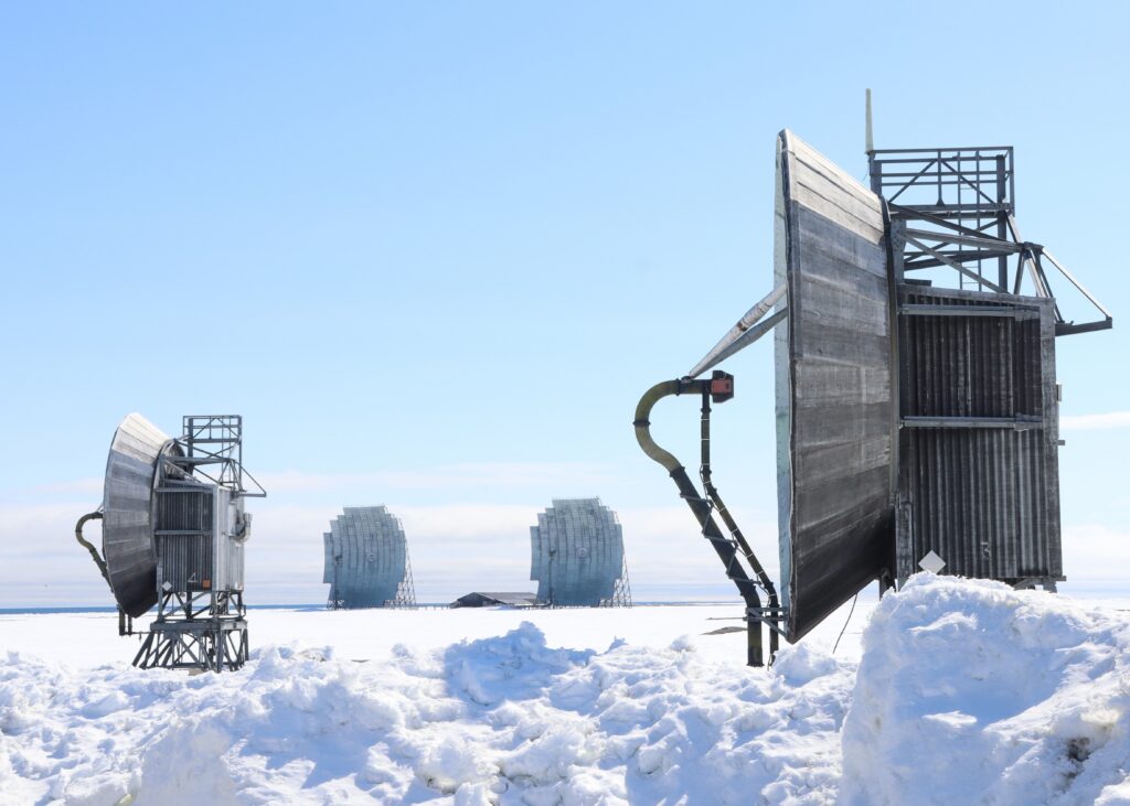 Multiple large grey parabolic antennae set in a snow-covered area.
