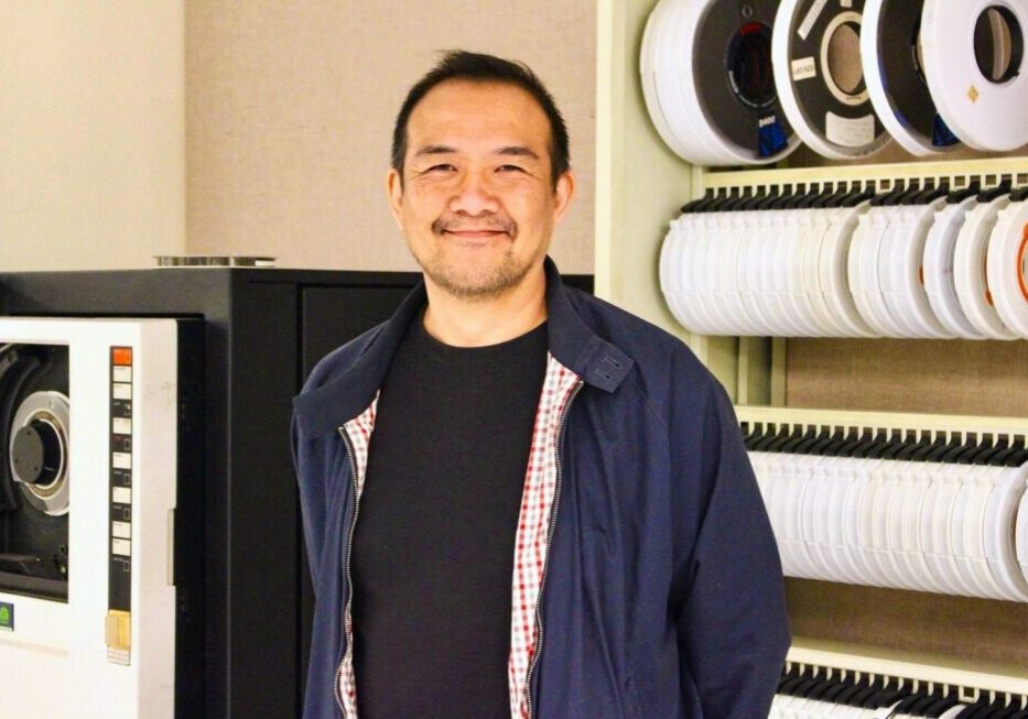 Diefenbunker 2024 Artist-in-Residence Don Kwan stands in front of historic computer equipment in the Diefenbunker.