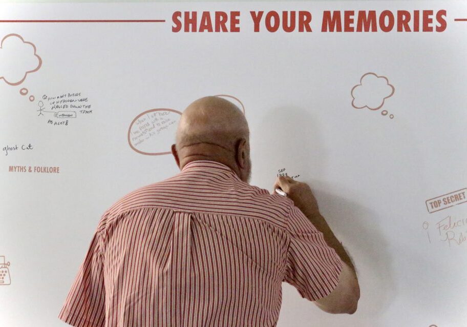 Guest writes on a board that says "Share Your Memories".