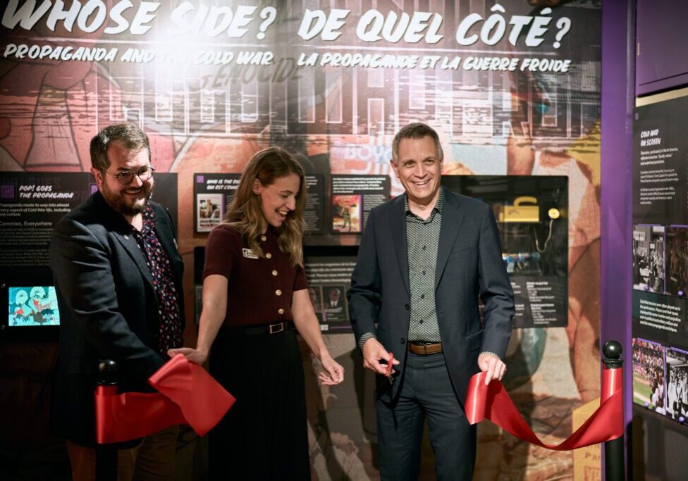 Three people smiling during a ribbon-cutting ceremony.