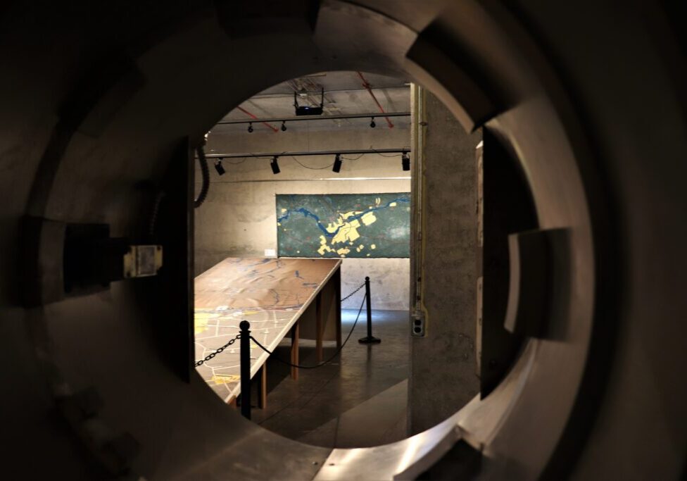 View through a circular window into a dimly lit skate park with a ramp.