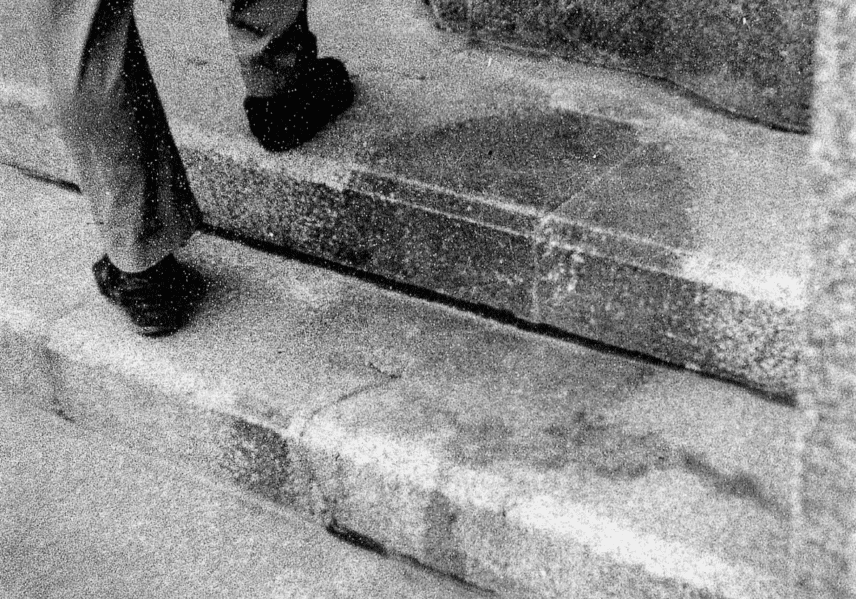Person stepping up concrete stairs, close-up on feet and steps.